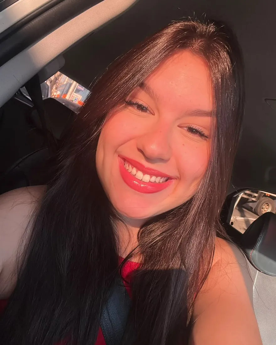 Giulya Xavier sorri, com o cabelo solto e batom vermelho
